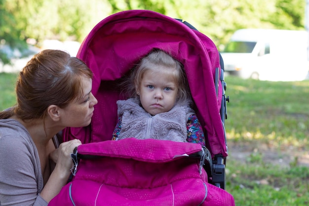 Donna che guarda la bambina offesa seduta nel passeggino