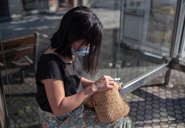 Donna che guarda la borsa alla fermata dell'autobus