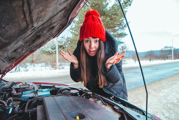 Donna che guarda la stagione invernale del concetto di assistenza stradale del motore dell'auto