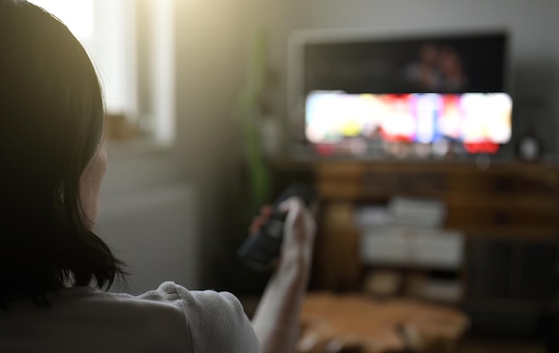 Donna che guarda la televisione a casa e mangia patatine