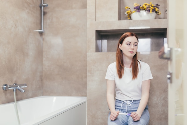 donna che guarda un rapido test di gravidanza con risultato positivo o negativo