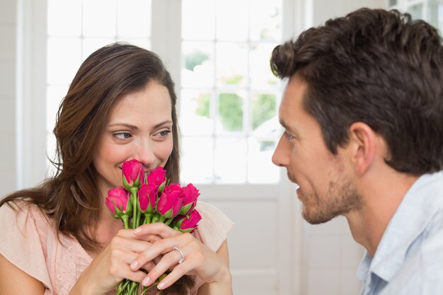 Donna che guarda uomo con fiori a casa