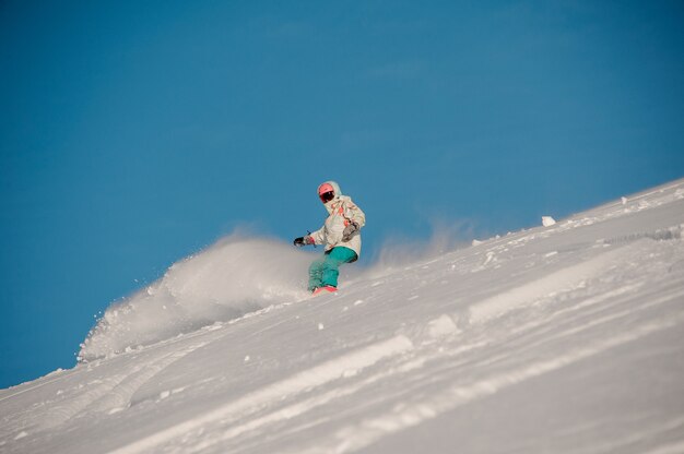 Donna che guida giù per la collina con lo snowboard nella famosa località turistica di Gudauri in Georgia