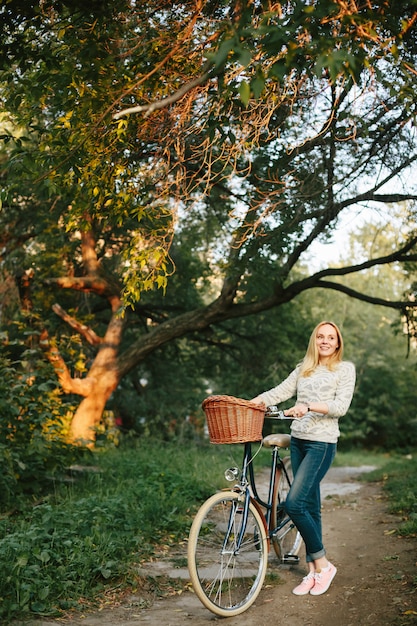 Donna che guida sulla bicicletta d'epoca con cesto