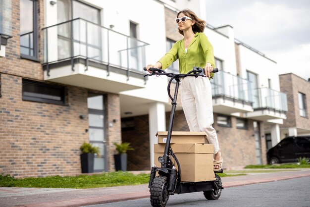 Donna che guida uno scooter elettrico con pacchetti di cartone