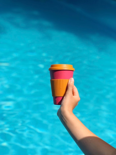 Donna che gusta il caffè in una tazza di bambù riutilizzabile in piscina Zero rifiuti di caffè da asporto