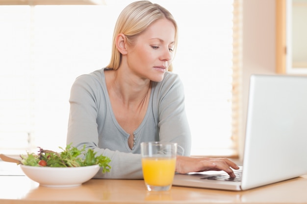 Donna che ha pranzo sano mentre si lavora sul suo computer portatile