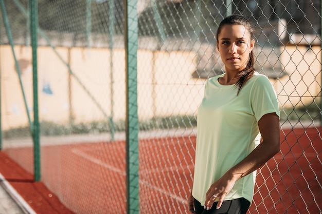 Donna che ha una pausa durante l'allenamento vicino al recinto di collegamento a catena