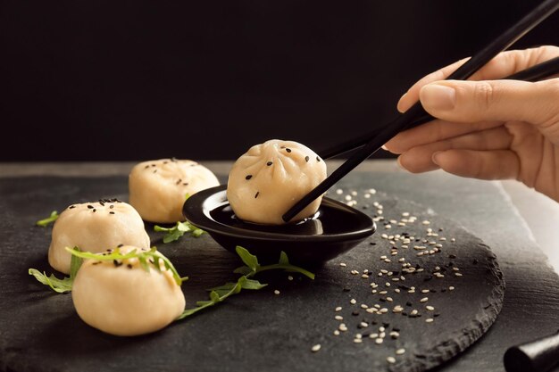 Donna che immerge gustosi gnocchi di baozi in salsa di soia a tavola