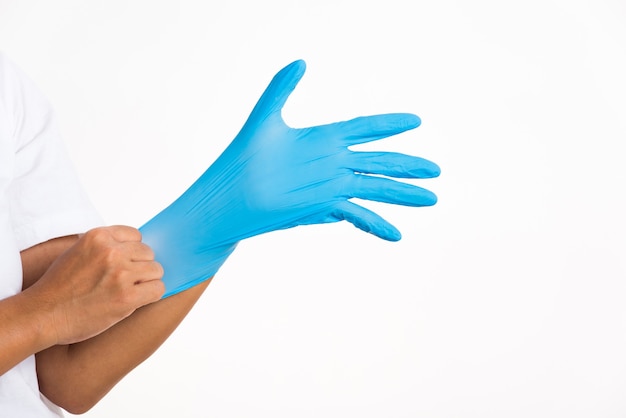 Donna che indossa e mette mano al guanto di lattice di gomma blu per il medico