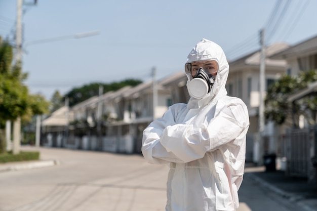 Donna che indossa guanti con tuta e maschera protettiva chimica a rischio biologico. Incrociò le braccia con la faccia infelice.