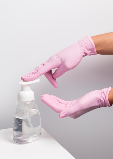 Donna che indossa guanti e utilizzando disinfettante per le mani