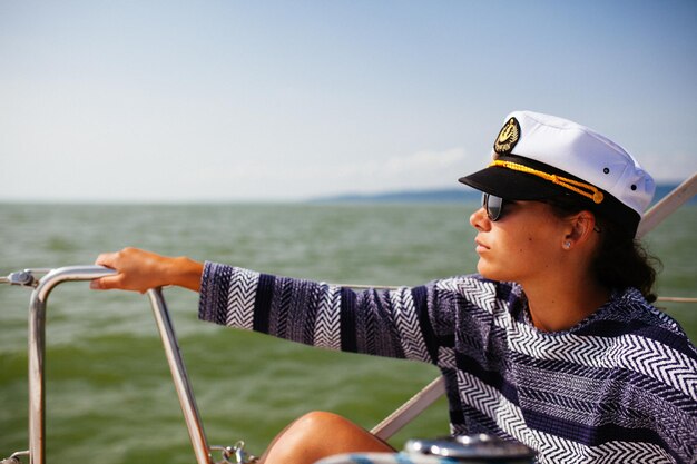 Donna che indossa il cappello di capitano in barca sul mare contro il cielo