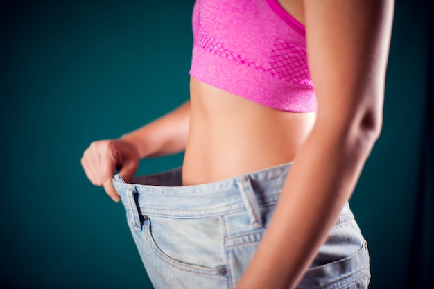 Donna che indossa jeans di grandi dimensioni. Perdita di peso, fitness e concetto di dieta