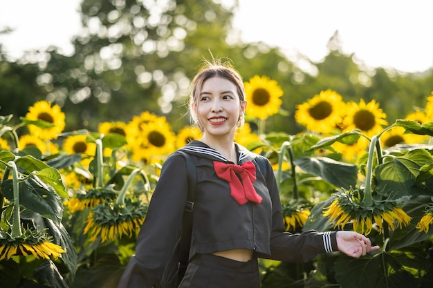 Donna che indossa l'uniforme scolastica giapponese cosplay al giardino di girasole all'aperto