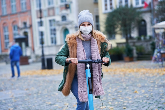 donna che indossa la maschera facciale e si sposta in scooter in città