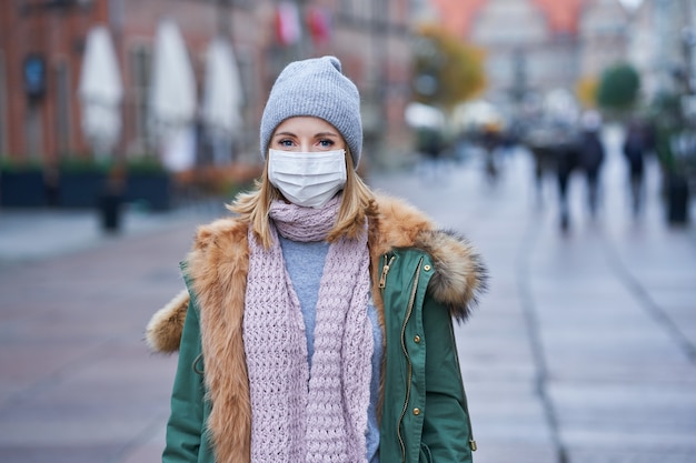 donna che indossa la maschera per il viso a causa dell'inquinamento atmosferico o dell'epidemia di virus in città