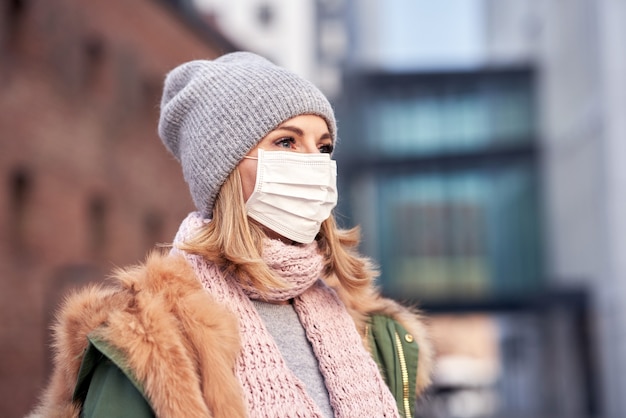 donna che indossa la maschera per il viso a causa dell'inquinamento atmosferico o dell'epidemia di virus in città