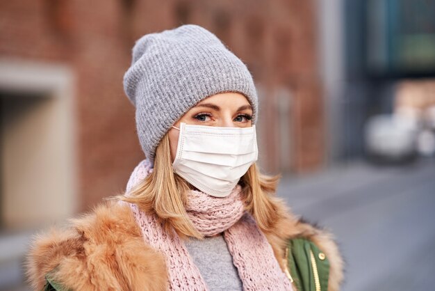 donna che indossa la maschera per il viso a causa dell'inquinamento atmosferico o dell'epidemia di virus in città