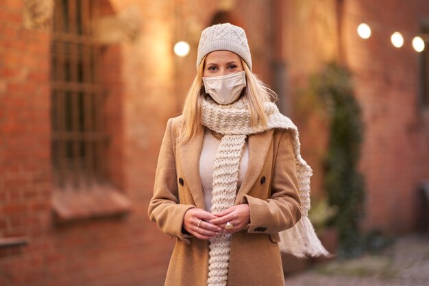 donna che indossa la maschera per il viso a causa dell'inquinamento atmosferico o dell'epidemia di virus in città