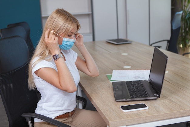 Donna che indossa la sua maschera protettiva al lavoro