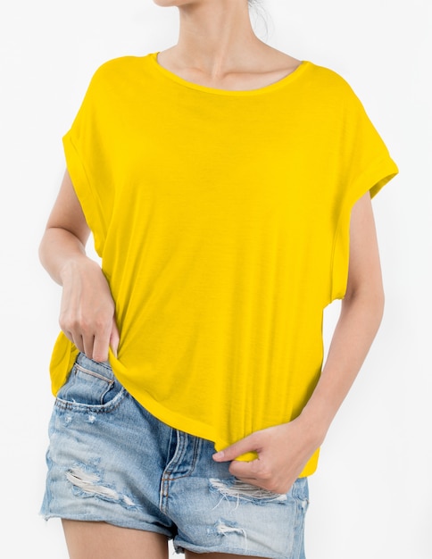 Donna che indossa maglietta gialla e brevi jeans dello strappo su bianco