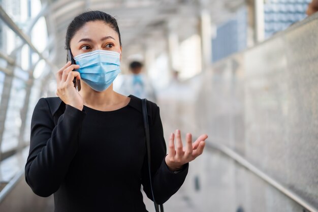 donna che indossa maschera medica e parla al cellulare