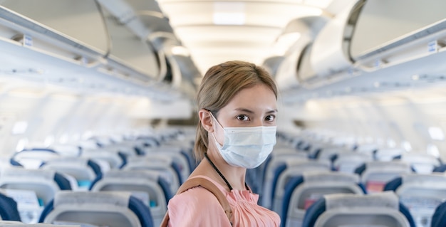 Donna che indossa maschere protettive che cammina a bordo di un aereo