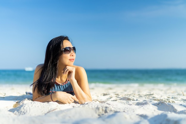 Donna che indossa occhiali da sole godendo spiaggia rilassante gioiosa in estate da acque blu tropicali con copia spazio