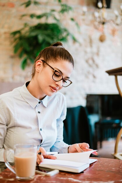 Donna che indossa occhiali leggendo al caffè.