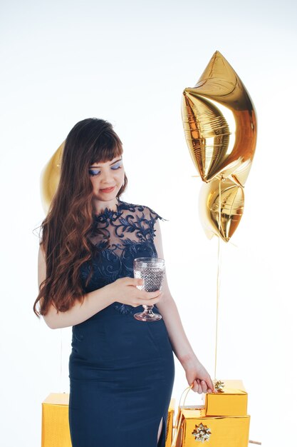 Donna che indossa un abito da sera con un bicchiere di champagne con una stella gonfiabile dorata