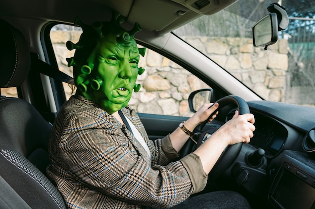 Donna che indossa un costume - maschera da coronavirus covid-19 alla guida di un'auto