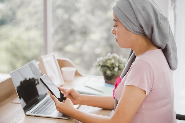 donna che indossa un laptop utilizzato hijab in tabella Allegando un nastro rosa guarigione da un cancro al seno