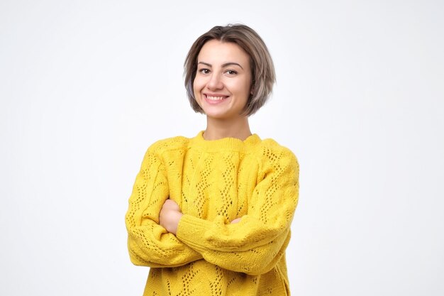 Donna che indossa un maglione giallo che sorride dolcemente mentre ascolta una conversazione interessante