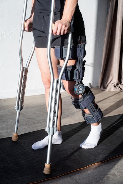 Donna che indossa un'ortesi per il ginocchio o un tutore per il supporto del ginocchio dopo l'intervento chirurgico sulla gamba