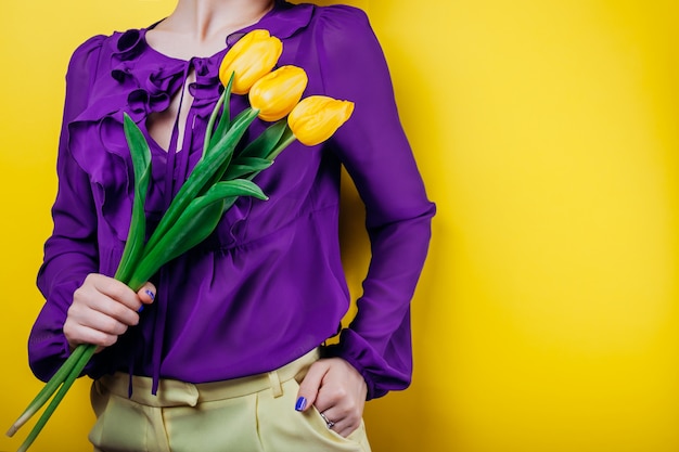 donna che indossa un vestito di primavera e in possesso di tulipani gialli