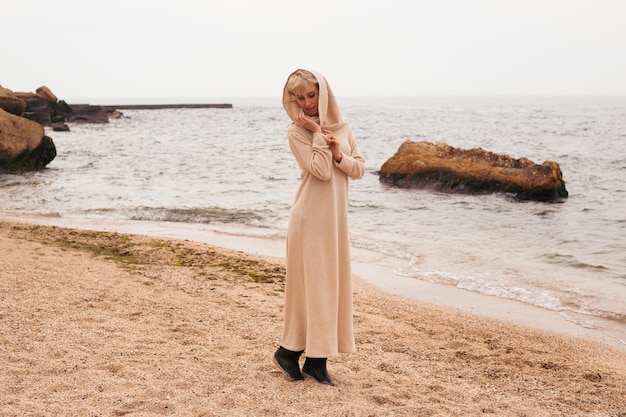 Donna che indossa un vestito vicino al mare in autunno