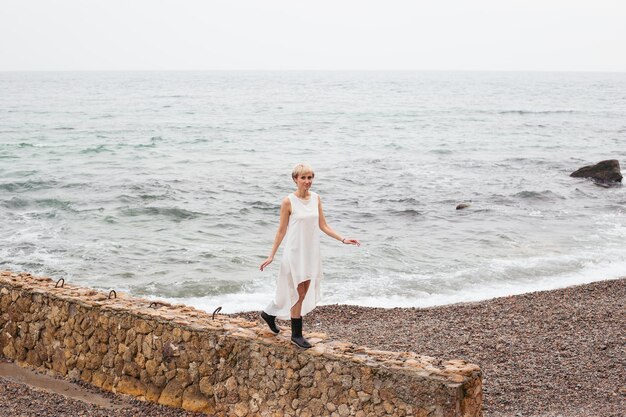 Donna che indossa un vestito vicino al mare in autunno