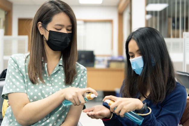 Donna che indossa una maschera e usando disinfettante