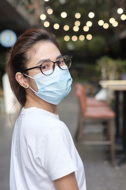 Donna che indossa una maschera medica durante la camminata nel sentiero per strada e nel mercato notturno, previene il coronavirus o la malattia da virus Corona (Covid-19). Salute, concetto di vita