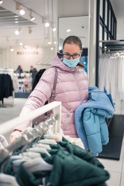 Donna che indossa una maschera protettiva per lo shopping di vestiti nel concetto di negozio di shopping al dettaglio di lifestyle du...