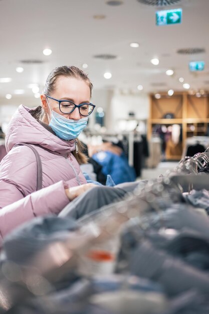 Donna che indossa una maschera protettiva per lo shopping di vestiti nel concetto di negozio di shopping al dettaglio di lifestyle du...