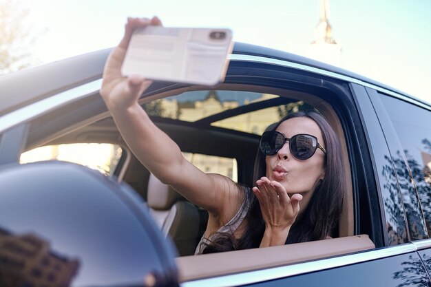 Donna che invia bacio volante mentre si fa selfie sullo smartphone