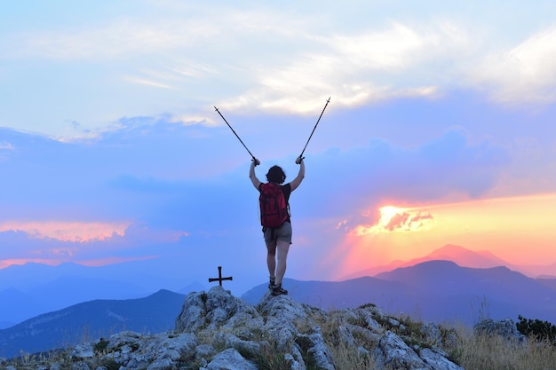 Donna che l'escursionista raggiunge la cima al tramonto