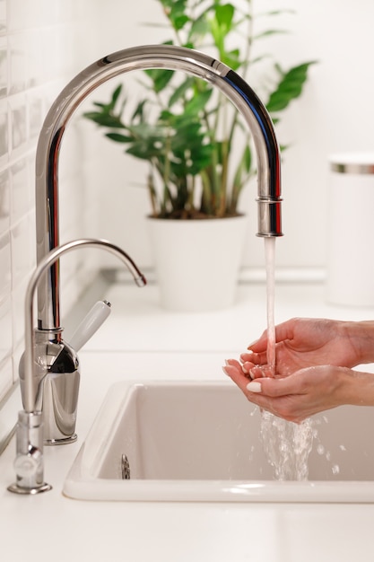 Donna che lava e che pulisce le sue mani sotto l'acqua di rubinetto scorrente