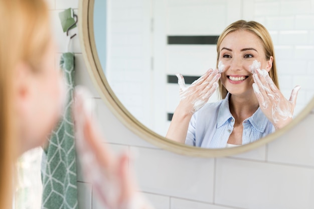 Donna che lava il viso nello specchio del bagno