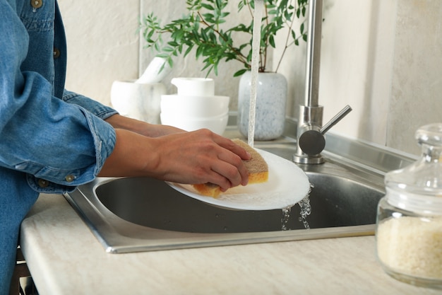 Donna che lava un piatto nel lavello della cucina