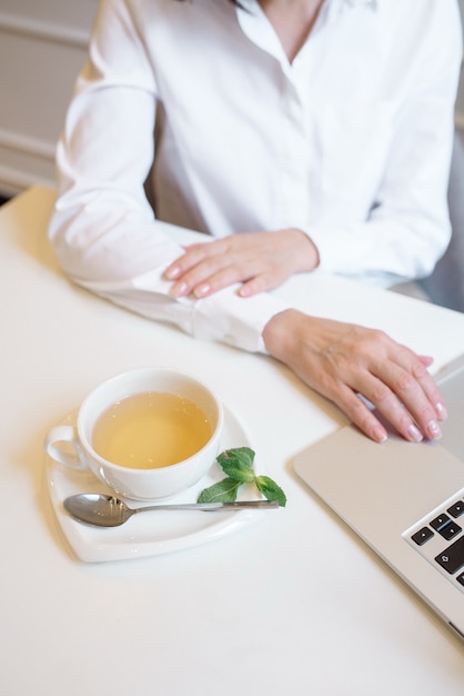 Donna che lavora a casa utilizzando laptop e bere tè verde alla menta