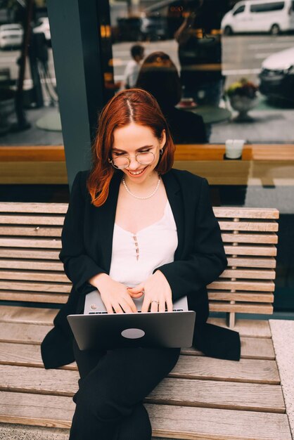 Donna che lavora al computer portatile che digita seduto nella caffetteria che beve caffè