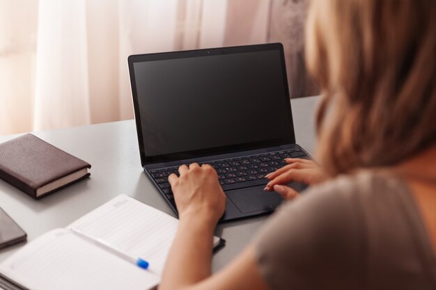 Donna che lavora al computer portatile con schermo nero